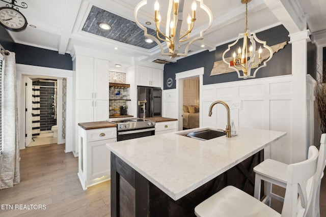 kitchen featuring electric range, decorative columns, black fridge with ice dispenser, a sink, and a notable chandelier