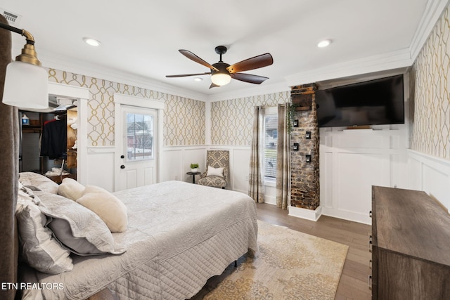 bedroom featuring wainscoting, crown molding, and wallpapered walls