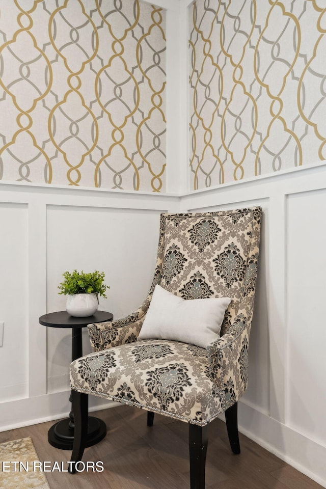 sitting room with a decorative wall and wood finished floors