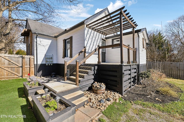 rear view of property featuring a lawn, stairs, a gate, fence, and a wooden deck