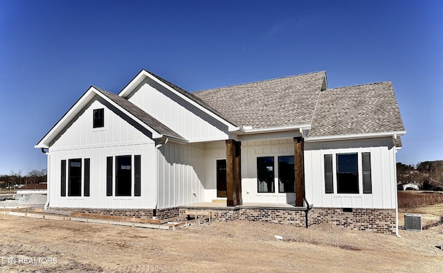 rear view of property featuring crawl space, a shingled roof, central AC, and board and batten siding