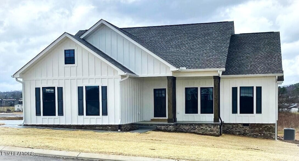 modern farmhouse style home featuring central air condition unit, roof with shingles, crawl space, board and batten siding, and a front yard