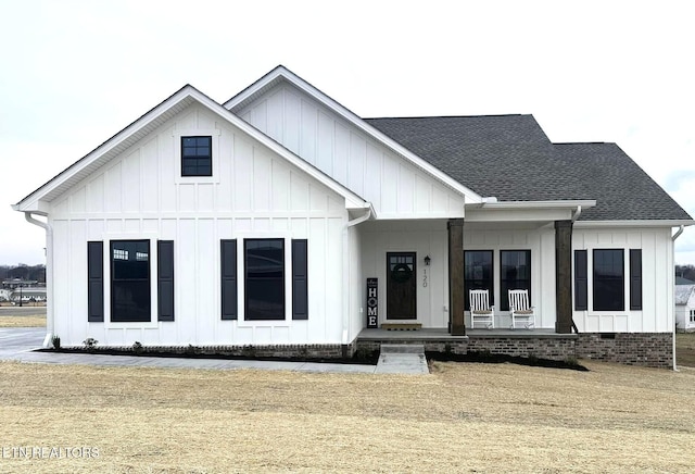 modern farmhouse with covered porch, board and batten siding, roof with shingles, and crawl space