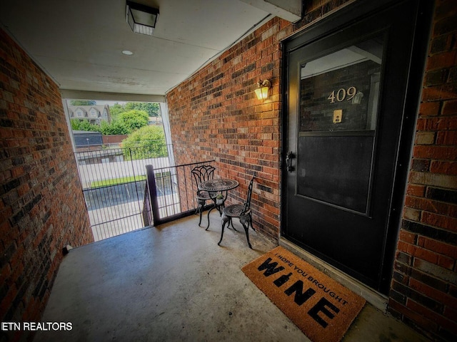 property entrance featuring covered porch and brick siding