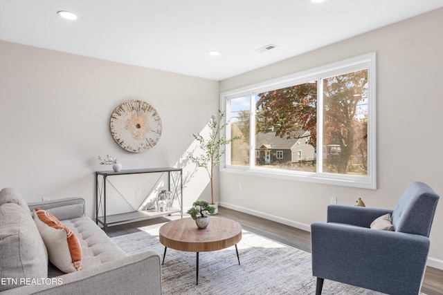 living room featuring baseboards, visible vents, wood finished floors, and recessed lighting