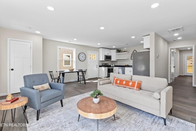 living area with recessed lighting, visible vents, baseboards, and wood finished floors