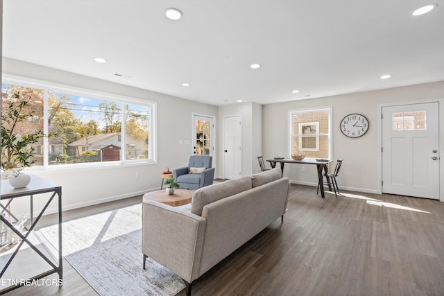 living area with recessed lighting, visible vents, baseboards, and wood finished floors