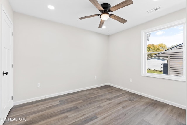 spare room with a ceiling fan, wood finished floors, visible vents, and baseboards