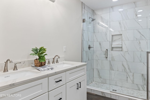 full bath with double vanity, a sink, and a shower stall