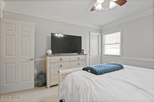 bedroom featuring ceiling fan, a textured ceiling, crown molding, and light colored carpet