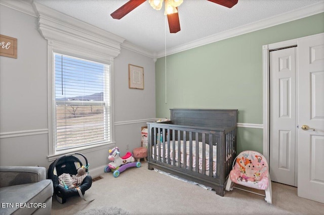 bedroom featuring visible vents, ornamental molding, a textured ceiling, carpet floors, and a nursery area