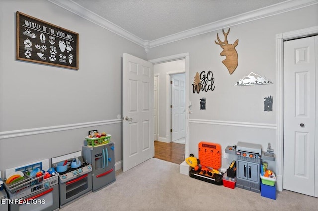 recreation room with carpet floors, a textured ceiling, and crown molding