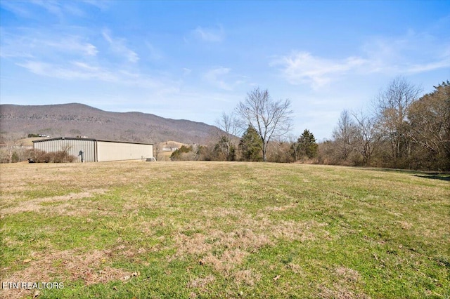 view of yard with a rural view, a pole building, a mountain view, and an outbuilding