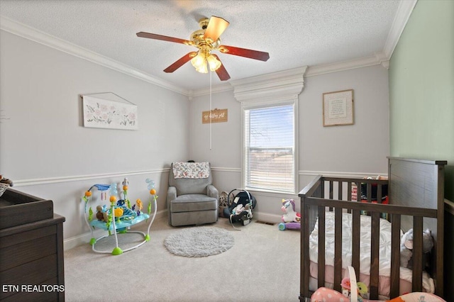 carpeted bedroom with a textured ceiling, a crib, baseboards, and crown molding