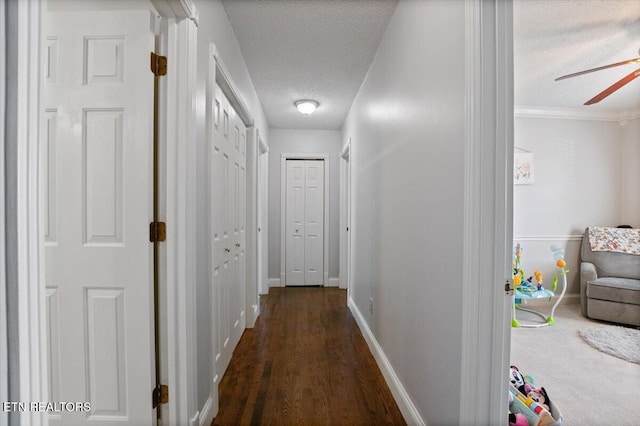 hallway with dark wood-style floors, baseboards, and a textured ceiling