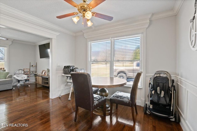 dining area with a wainscoted wall, dark wood-type flooring, a decorative wall, and crown molding