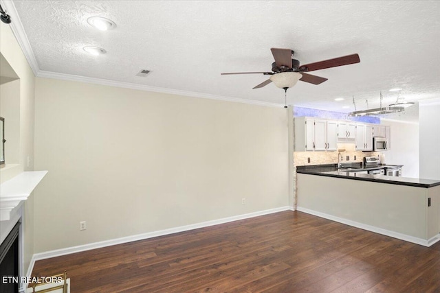 unfurnished living room featuring a sink, visible vents, baseboards, dark wood-style floors, and crown molding