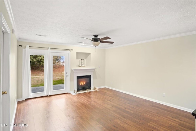 unfurnished living room featuring ornamental molding, a glass covered fireplace, and wood finished floors