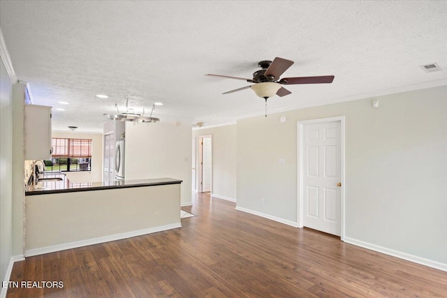 interior space with ornamental molding, visible vents, a textured ceiling, and wood finished floors