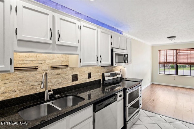 kitchen featuring a textured ceiling, a sink, white cabinetry, appliances with stainless steel finishes, and tasteful backsplash