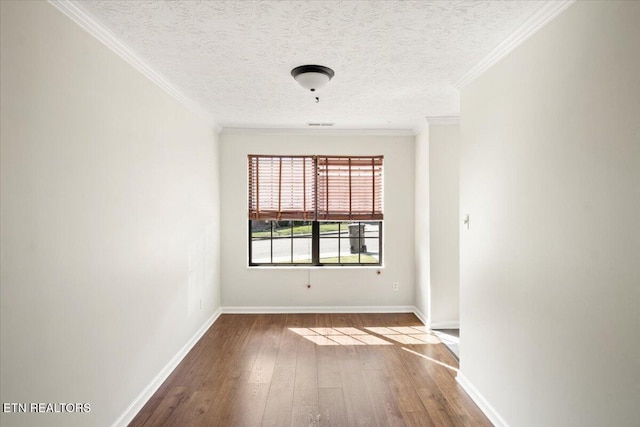 unfurnished room with wood-type flooring, a textured ceiling, ornamental molding, and baseboards