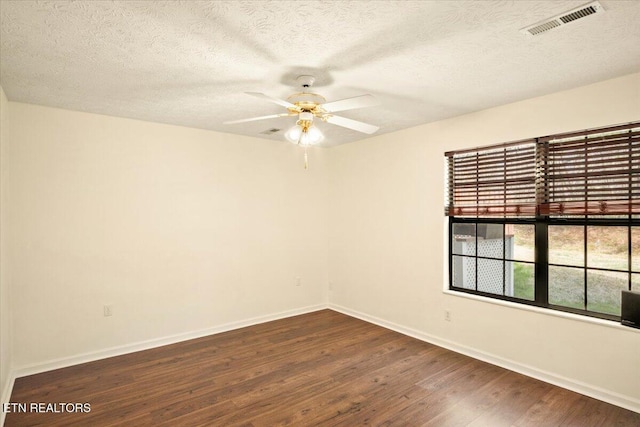 unfurnished room featuring dark wood-type flooring, visible vents, a textured ceiling, and baseboards