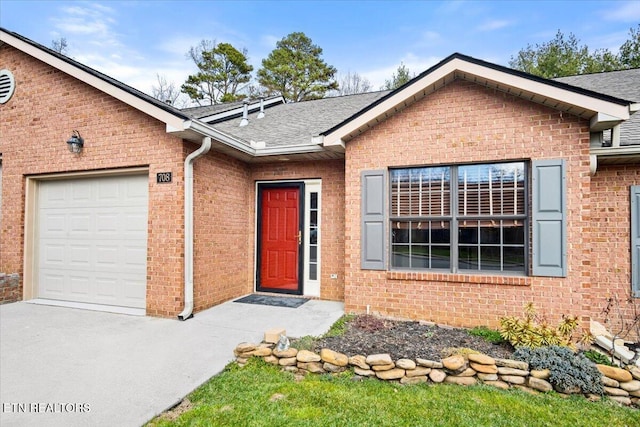 single story home featuring an attached garage, a shingled roof, and brick siding