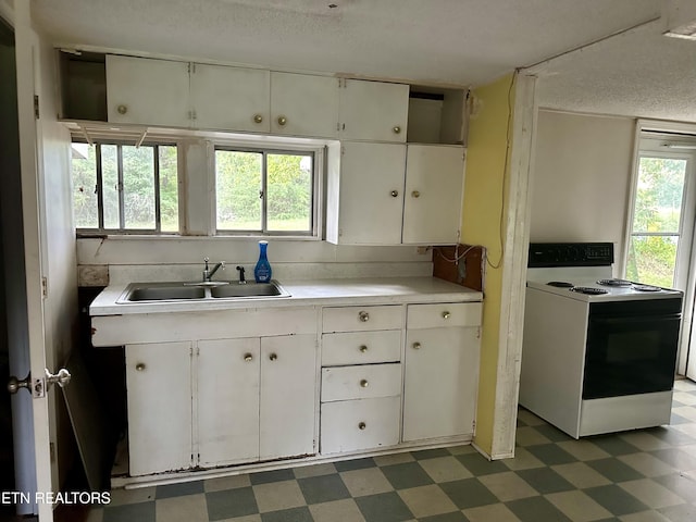 kitchen with dark floors, light countertops, electric range, white cabinetry, and a sink