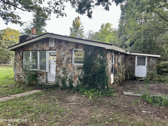 view of front of home featuring stone siding and a chimney