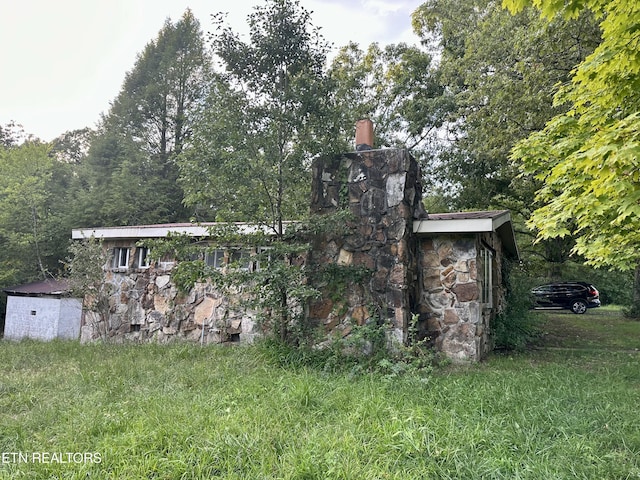 exterior space with stone siding and a chimney