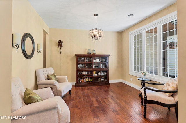 sitting room with an inviting chandelier, dark wood-type flooring, baseboards, and visible vents