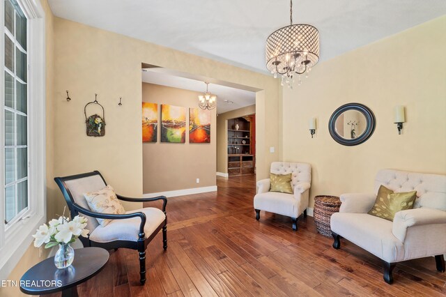 sitting room with baseboards, an inviting chandelier, and hardwood / wood-style flooring