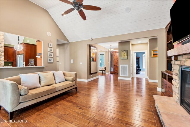 living room featuring built in features, visible vents, baseboards, a fireplace, and hardwood / wood-style flooring