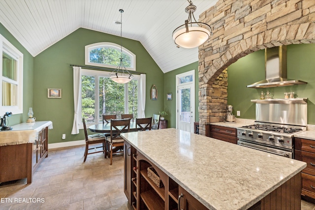 kitchen featuring a center island, wall chimney range hood, vaulted ceiling, stainless steel stove, and open shelves