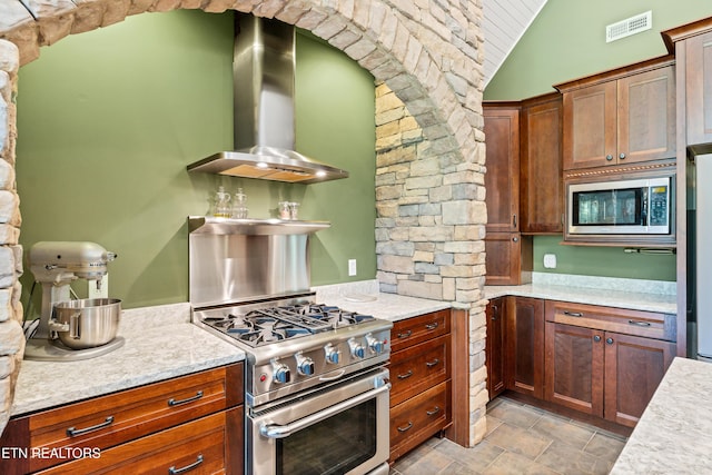 kitchen featuring stainless steel appliances, lofted ceiling, visible vents, and wall chimney range hood