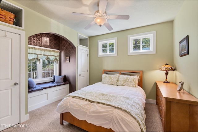 carpeted bedroom featuring multiple windows, baseboards, and ceiling fan