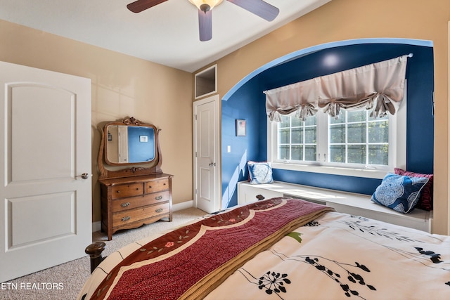 carpeted bedroom featuring baseboards, arched walkways, and a ceiling fan