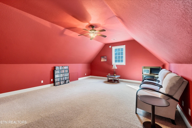 unfurnished room with a textured ceiling, carpet, baseboards, ceiling fan, and vaulted ceiling