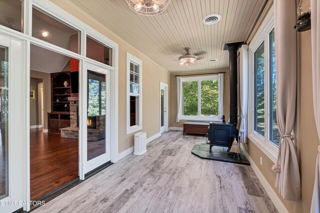 sunroom / solarium featuring wooden ceiling, a wood stove, and visible vents