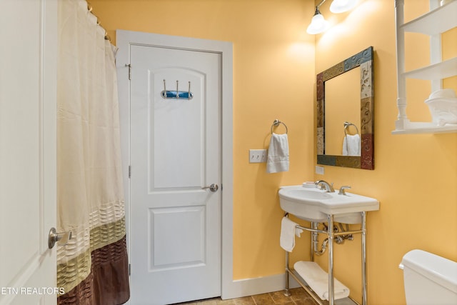 full bathroom with curtained shower, baseboards, and toilet