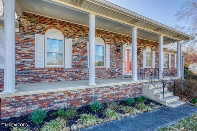 property entrance with brick siding and covered porch