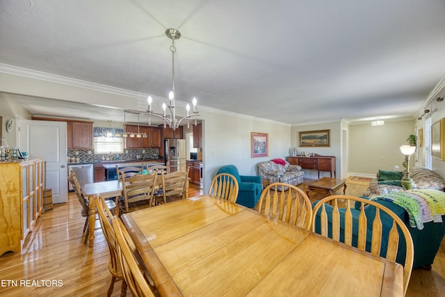 dining space with a notable chandelier, light wood-type flooring, and ornamental molding