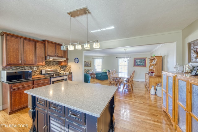 kitchen featuring electric range, under cabinet range hood, a kitchen island, light wood finished floors, and decorative backsplash