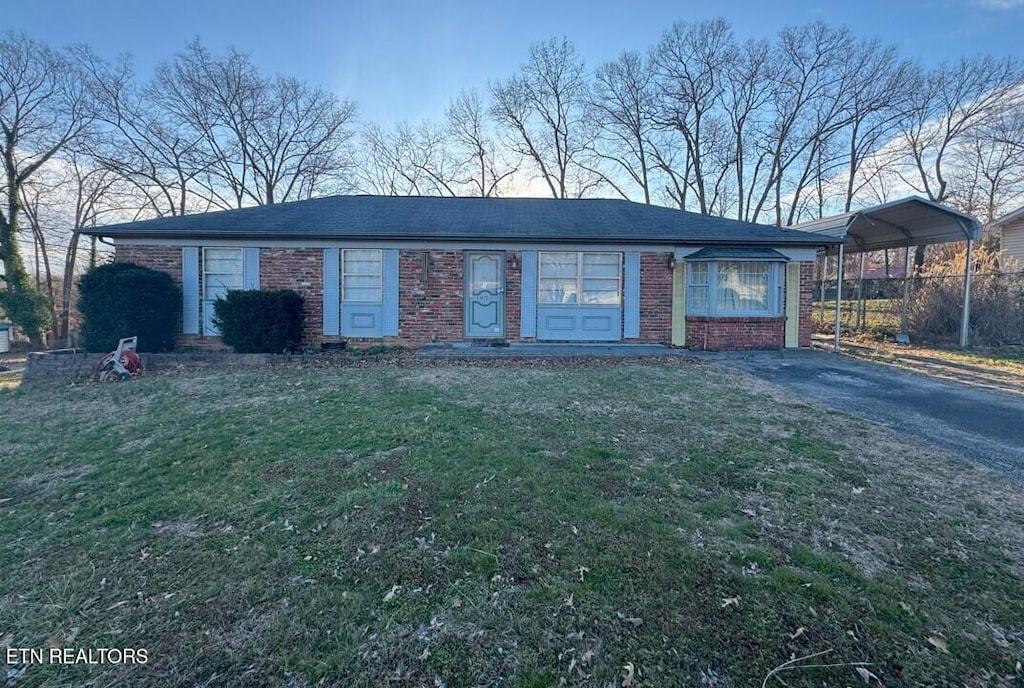 ranch-style home with aphalt driveway, a detached carport, brick siding, and a front lawn