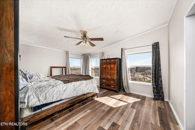 bedroom featuring baseboards, a ceiling fan, ornamental molding, wood finished floors, and a textured ceiling