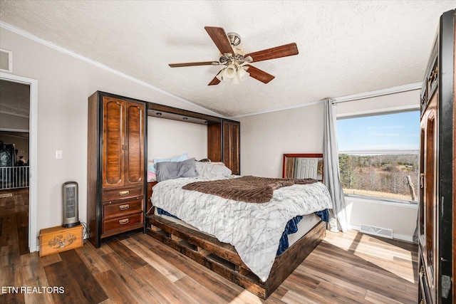 bedroom featuring visible vents, vaulted ceiling, dark wood finished floors, and ornamental molding