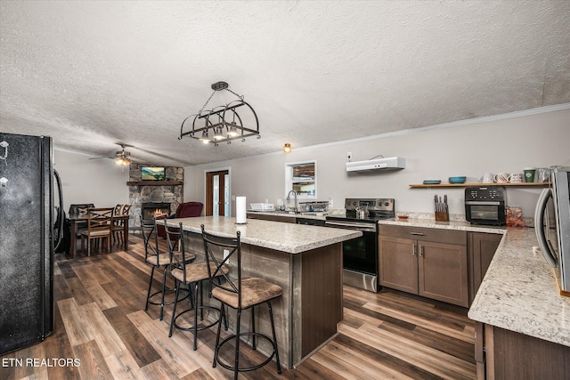 kitchen with stainless steel electric range oven, a fireplace, dark wood-type flooring, and freestanding refrigerator