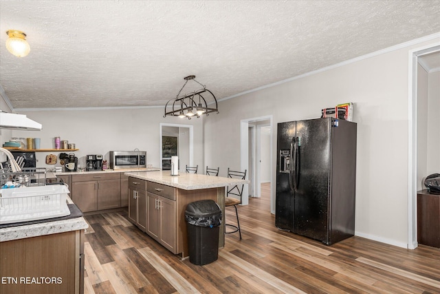 kitchen featuring dark wood-style floors, stainless steel microwave, a sink, a chandelier, and black fridge