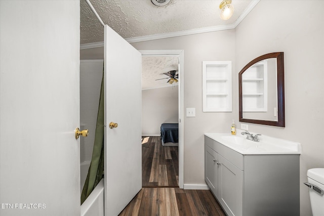 ensuite bathroom with toilet, ornamental molding, a textured ceiling, vanity, and wood finished floors