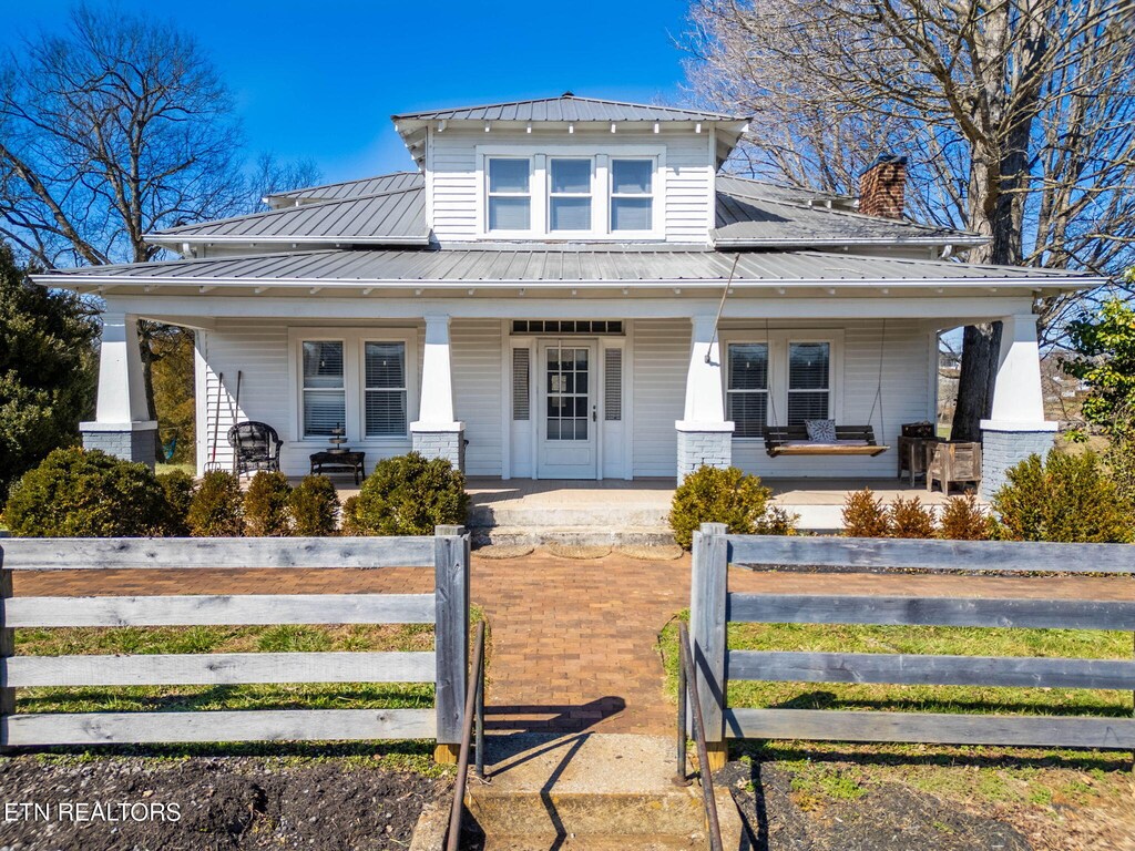 view of front of house with metal roof, a porch, and a fenced front yard